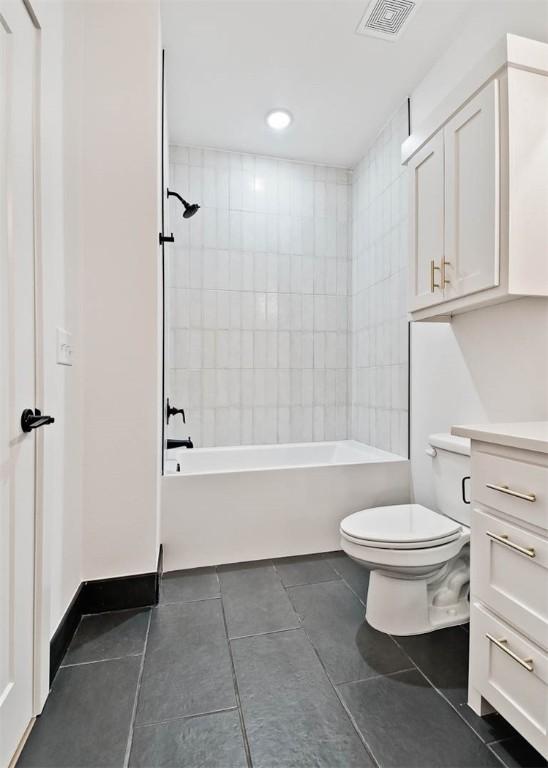 full bathroom with tiled shower / bath combo, vanity, tile patterned flooring, and toilet