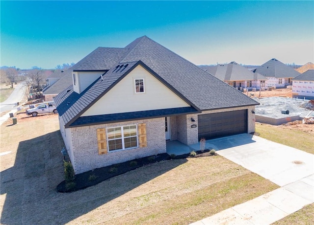 view of front of house with brick siding, a front lawn, roof with shingles, a garage, and driveway