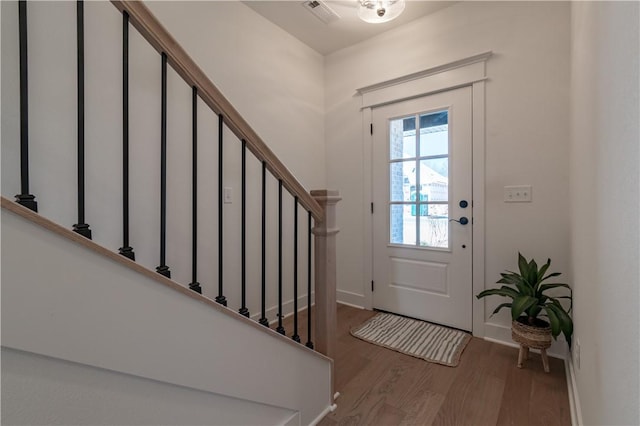 foyer with stairway, wood finished floors, visible vents, and baseboards