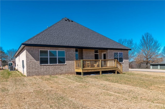 rear view of property with a deck, a yard, cooling unit, and brick siding