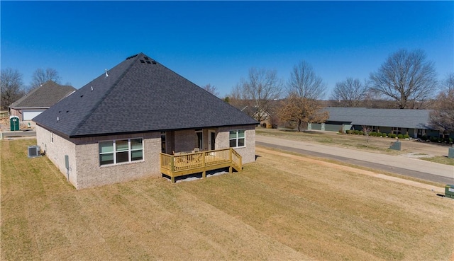 rear view of property featuring a deck, a yard, central AC unit, and brick siding