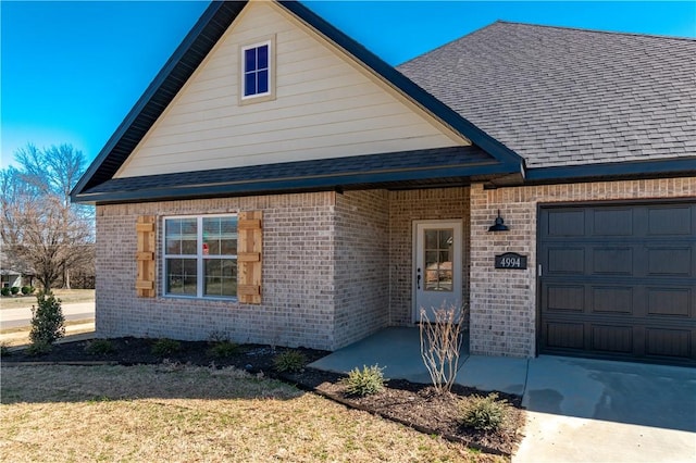 view of front of house featuring brick siding, an attached garage, and roof with shingles