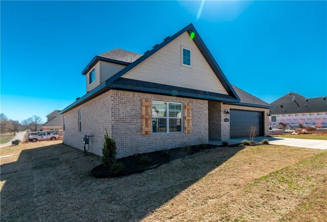 view of side of property featuring a garage, a lawn, brick siding, and driveway