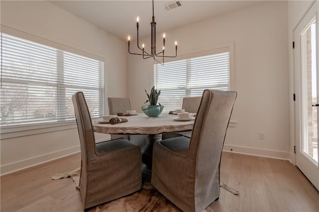 dining area with an inviting chandelier, baseboards, visible vents, and light wood-type flooring