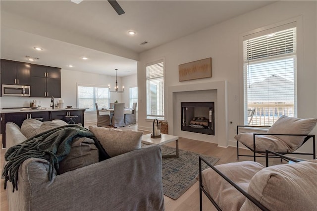 living room featuring light wood finished floors, visible vents, recessed lighting, and a fireplace