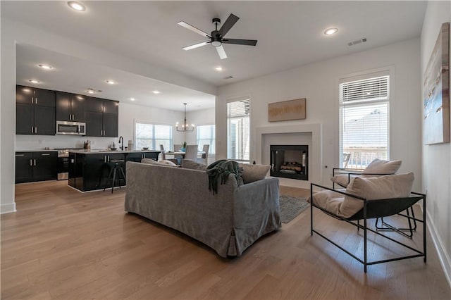 living room featuring light wood finished floors, visible vents, recessed lighting, and a fireplace