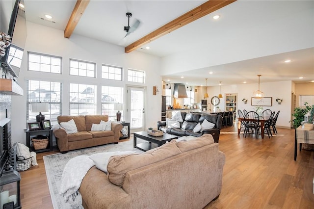 living room with beamed ceiling, plenty of natural light, and light hardwood / wood-style floors