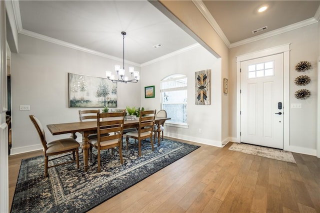 dining area with crown molding, a chandelier, hardwood / wood-style floors, and a wealth of natural light