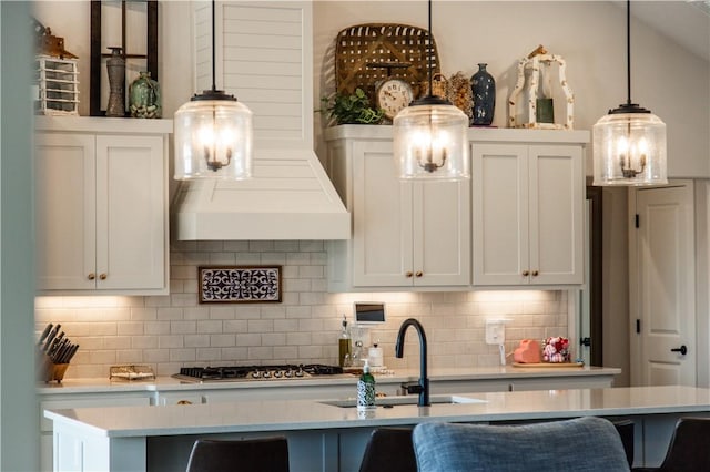 kitchen with tasteful backsplash, pendant lighting, sink, and a center island with sink