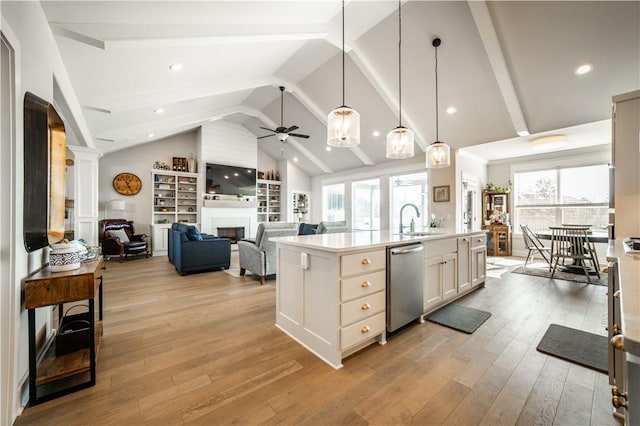 kitchen with sink, hanging light fixtures, stainless steel dishwasher, a kitchen island with sink, and white cabinets