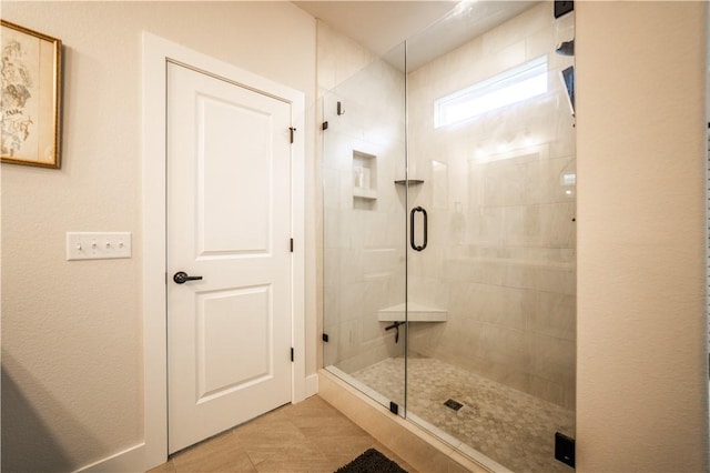 bathroom with a shower with door and tile patterned floors