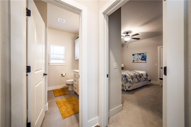 bedroom featuring ensuite bath, light colored carpet, and ceiling fan