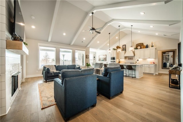 living room with ceiling fan, vaulted ceiling, and light wood-type flooring