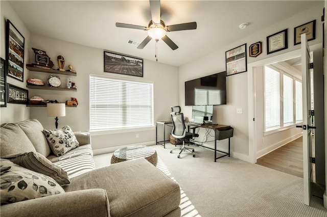 carpeted office space with ceiling fan