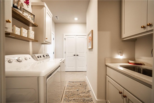 clothes washing area featuring separate washer and dryer, light tile patterned floors, sink, and cabinets