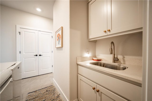 washroom featuring cabinets, sink, light tile patterned floors, and washing machine and clothes dryer