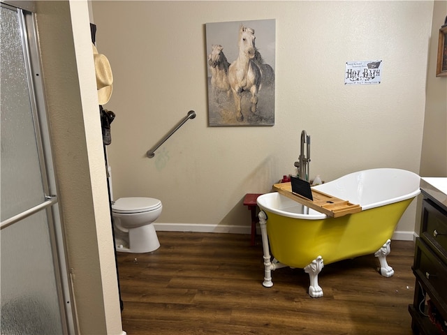 bathroom featuring vanity, a tub to relax in, wood-type flooring, and toilet