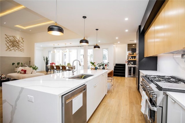 kitchen with sink, decorative light fixtures, a center island with sink, stainless steel appliances, and light stone countertops