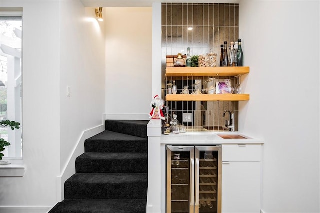 bar featuring wine cooler, sink, and decorative backsplash