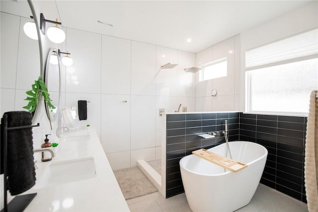 bathroom with tile patterned floors, independent shower and bath, tile walls, and vanity