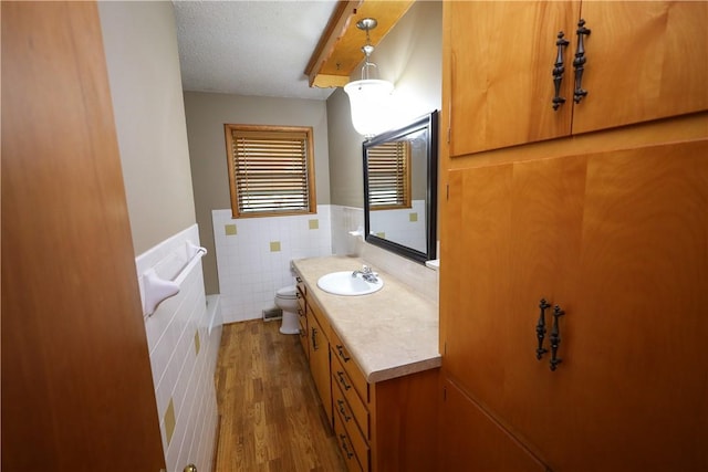 bathroom with tile walls, hardwood / wood-style floors, vanity, a textured ceiling, and toilet