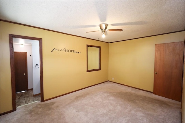 carpeted empty room featuring ceiling fan, crown molding, and a textured ceiling