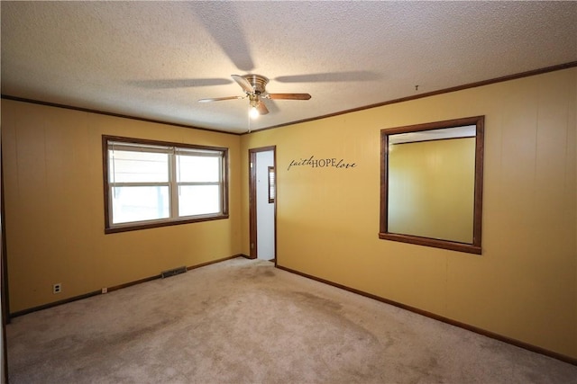 empty room featuring ornamental molding, light carpet, ceiling fan, and a textured ceiling