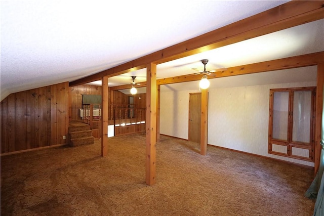 interior space featuring ceiling fan, wooden walls, and carpet