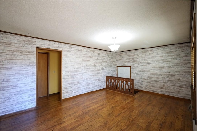 unfurnished room featuring crown molding, dark wood-type flooring, and a textured ceiling