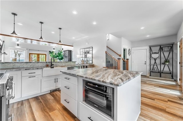 kitchen featuring sink, white cabinetry, a kitchen island, pendant lighting, and decorative backsplash