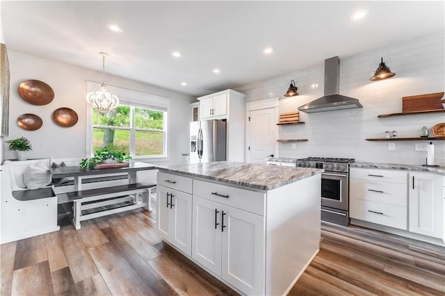 kitchen featuring appliances with stainless steel finishes, island exhaust hood, tasteful backsplash, white cabinets, and a kitchen island