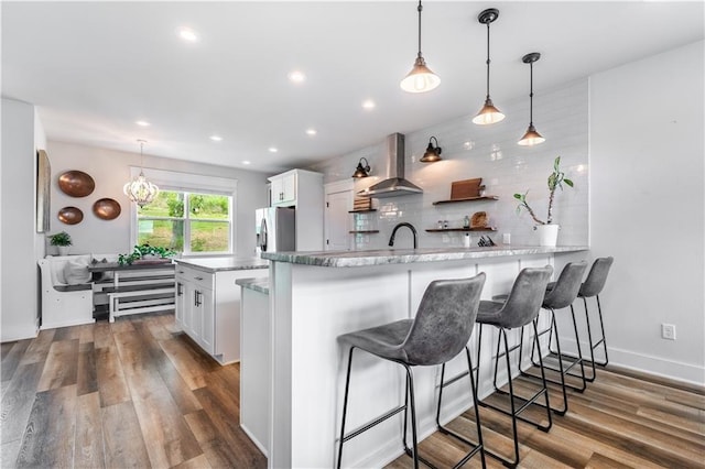 kitchen with extractor fan, white cabinetry, decorative backsplash, hanging light fixtures, and kitchen peninsula