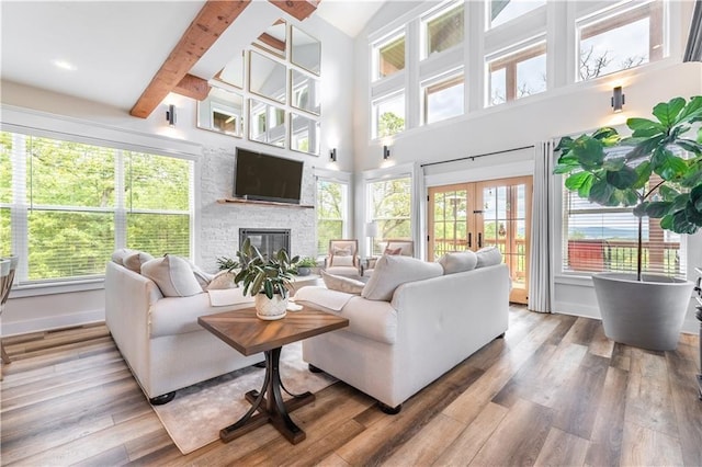 living room featuring hardwood / wood-style flooring, beam ceiling, a fireplace, and french doors