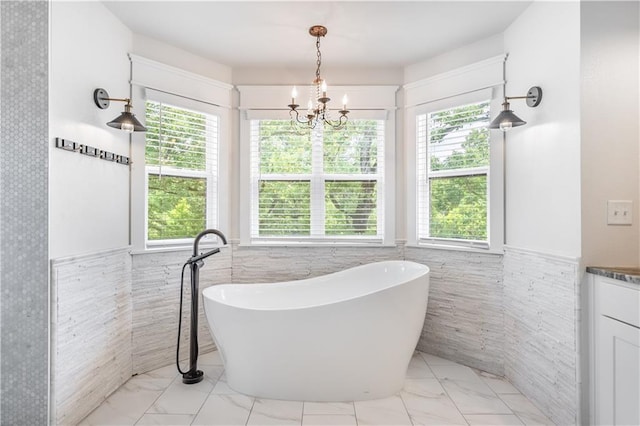 bathroom featuring tile walls, a tub to relax in, vanity, and a notable chandelier