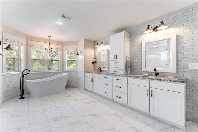 bathroom featuring vanity, a notable chandelier, and a bathing tub