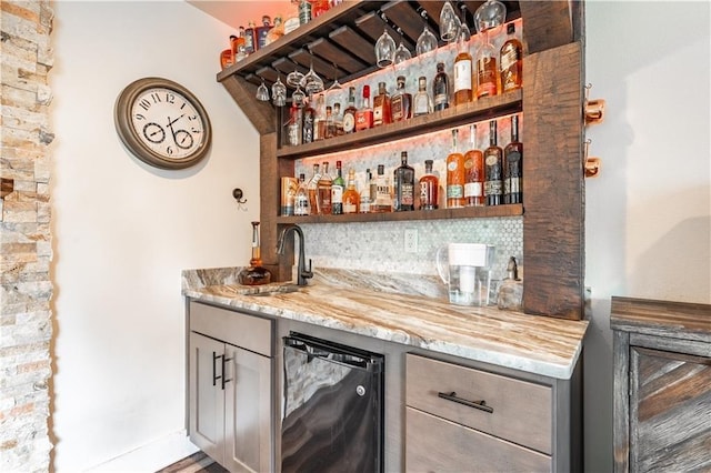 bar featuring beverage cooler, sink, and decorative backsplash