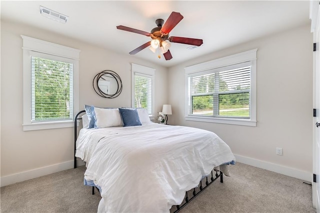 carpeted bedroom with multiple windows and ceiling fan