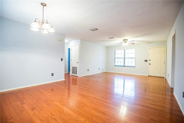 empty room featuring hardwood / wood-style flooring, ceiling fan with notable chandelier, and a textured ceiling