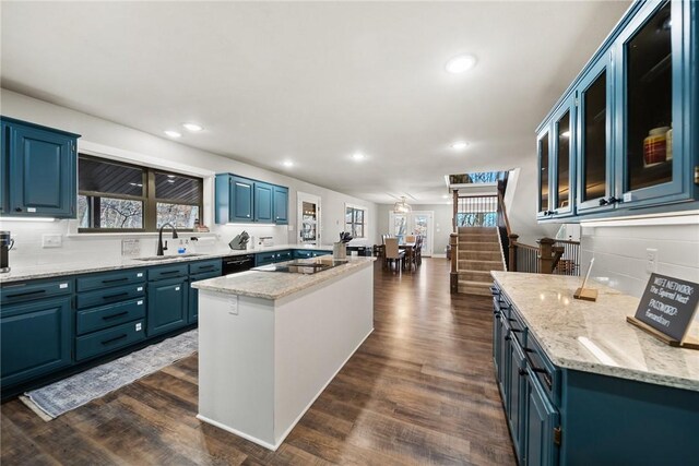 kitchen featuring dark hardwood / wood-style floors, blue cabinets, sink, a center island, and light stone countertops