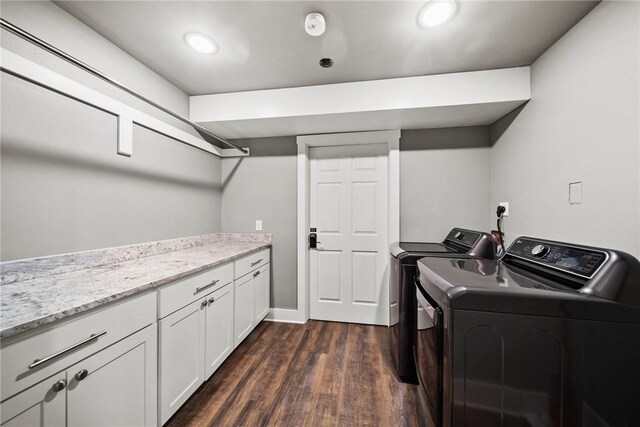 laundry area featuring cabinets, washing machine and dryer, and dark hardwood / wood-style floors