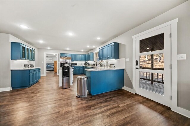 kitchen featuring sink, stainless steel fridge, dark wood-type flooring, kitchen peninsula, and blue cabinetry