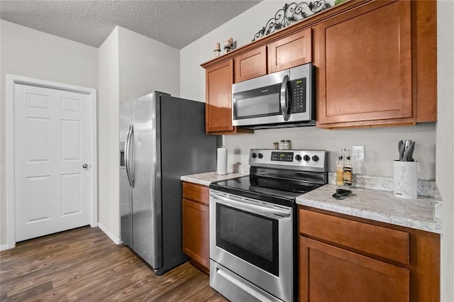 kitchen featuring dark hardwood / wood-style flooring, light stone counters, a textured ceiling, and appliances with stainless steel finishes