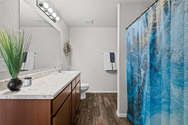 bathroom featuring hardwood / wood-style floors, vanity, toilet, a textured ceiling, and a shower with shower curtain