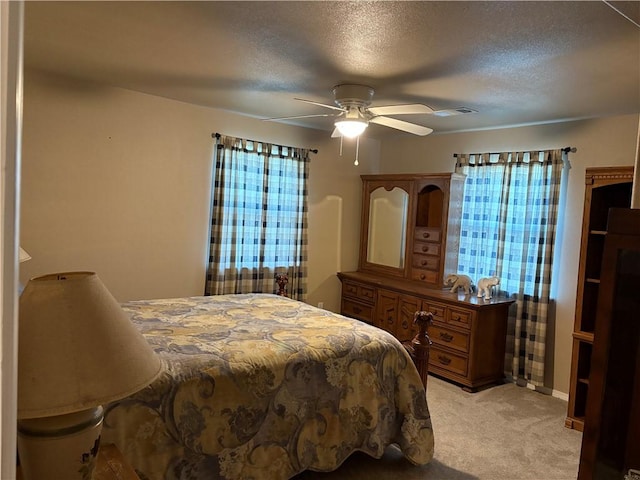 bedroom with light carpet, multiple windows, a textured ceiling, and a ceiling fan