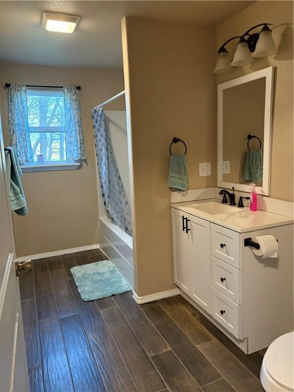 bathroom featuring shower / tub combo, baseboards, toilet, wood tiled floor, and vanity