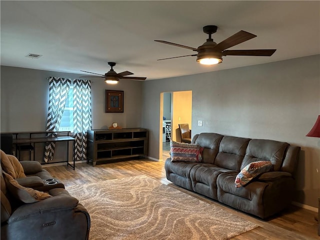 living area featuring wood finished floors, baseboards, a ceiling fan, and visible vents