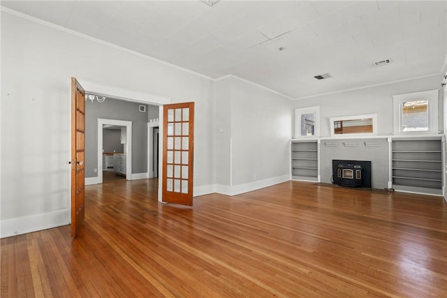 unfurnished living room featuring crown molding, wood-type flooring, and french doors