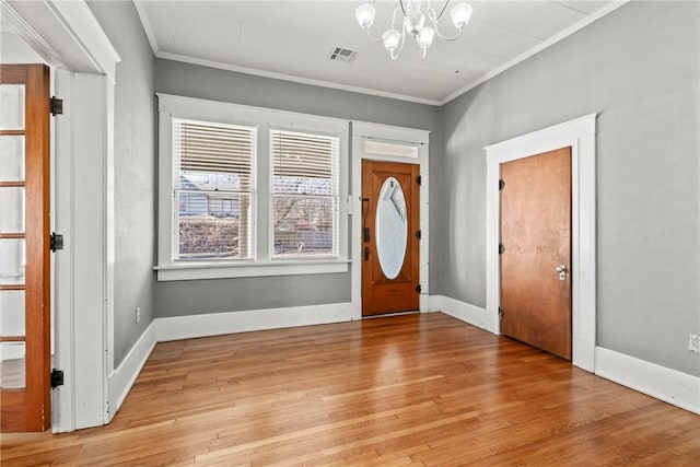entrance foyer with ornamental molding, a notable chandelier, and light hardwood / wood-style floors