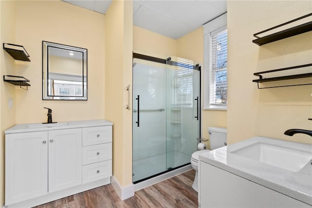 bathroom featuring vanity, wood-type flooring, a shower with door, and toilet