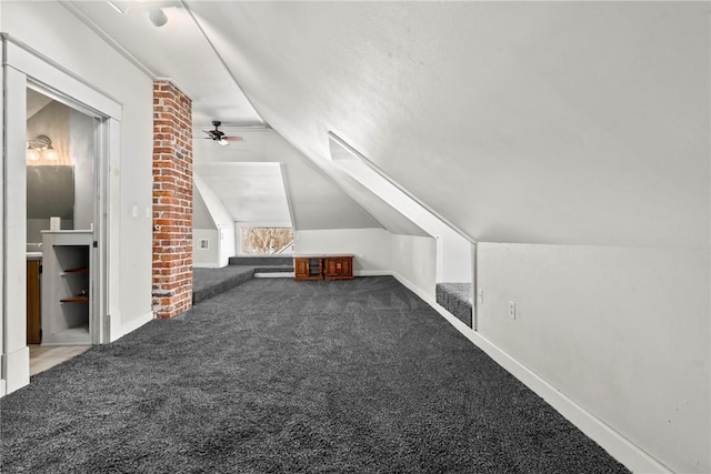 additional living space featuring dark carpet and vaulted ceiling